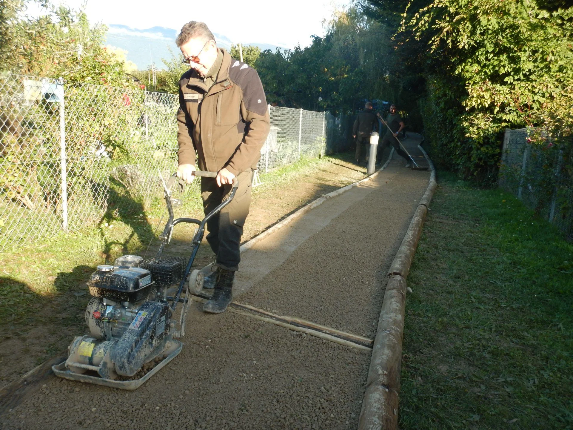 Un membre de l’ORPC utilise une plaque vibrante pour remettre en état un chemin.